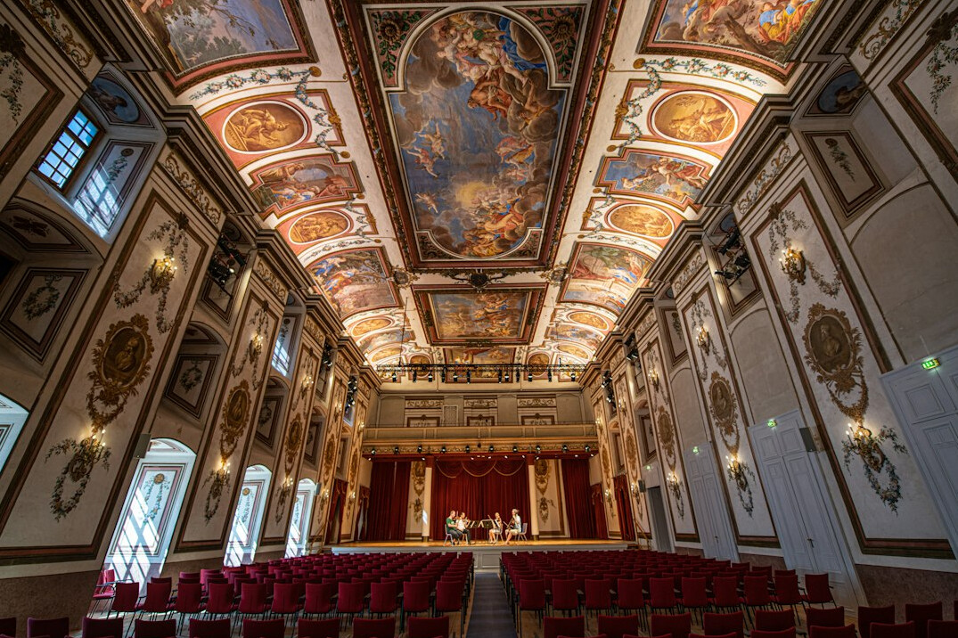Interior of a grand theater hall with red seats and ornate ceiling